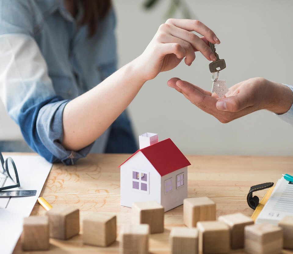 A woman handing over the house key to a man